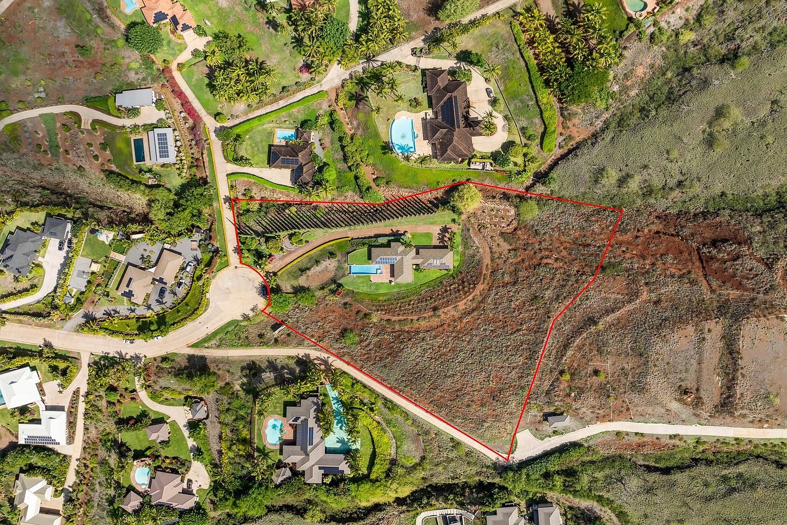 This aerial view showcases a large residential property, highlighting the expansive lot size and the layout of the home and surrounding landscape. The property features a well-maintained lawn, a swimming pool, and mature trees, all enclosed within a defined boundary. The image emphasizes the privacy and exclusivity of the estate.