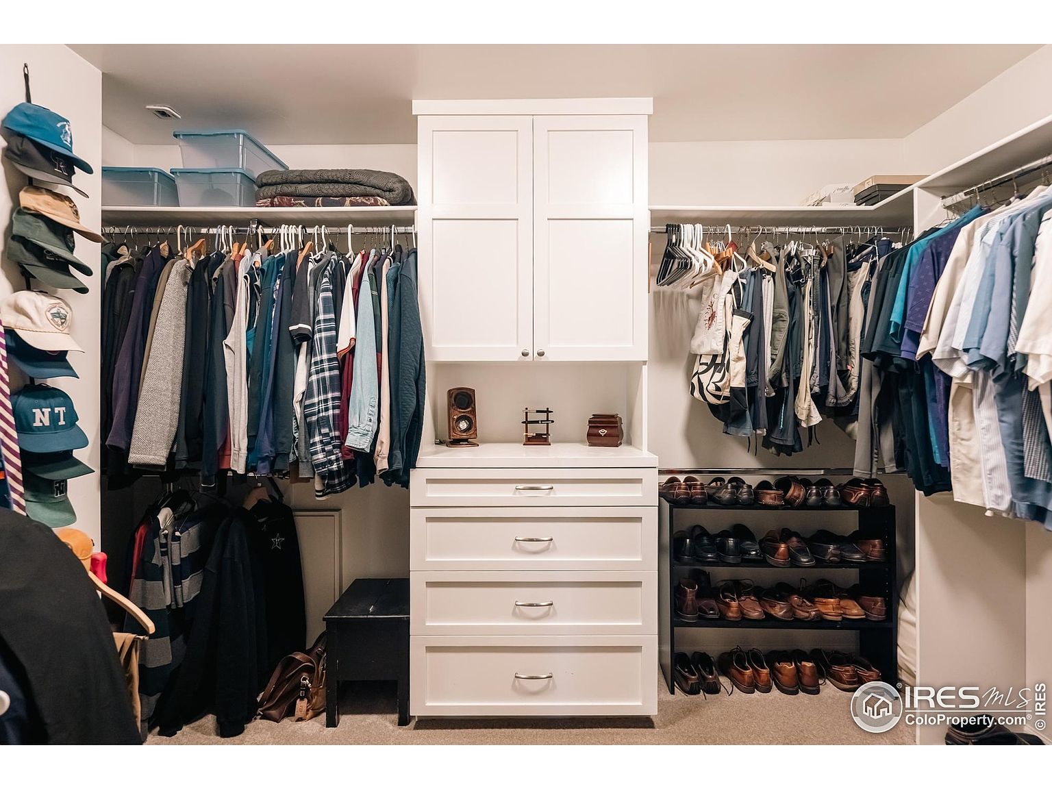 This is a well-organized walk-in closet featuring custom shelving and storage solutions. The closet includes hanging rods for clothing, drawers for folded items, and shoe racks. The overall impression is neat and efficient, maximizing storage space.
