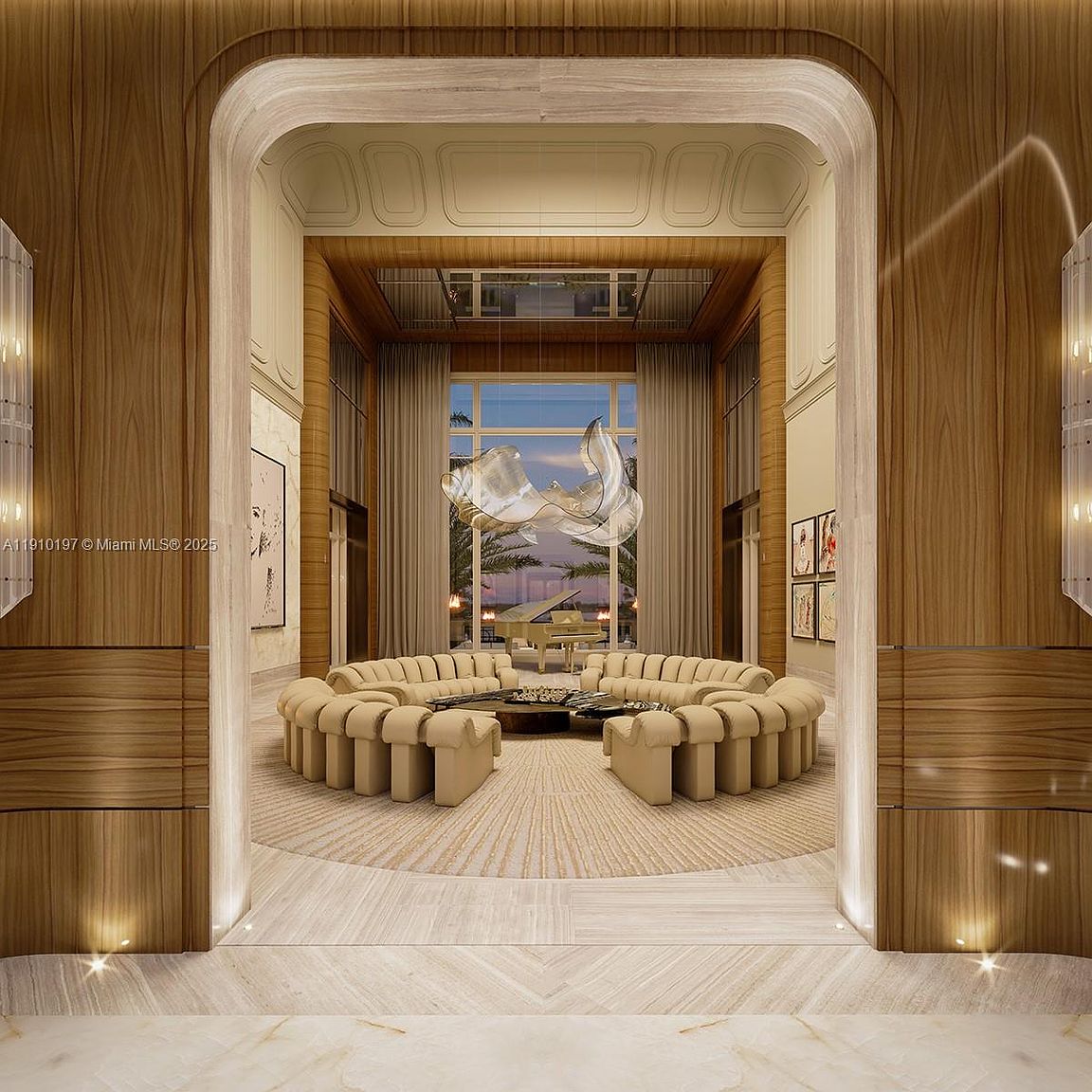 This is a luxurious living room featuring a large, circular sofa arrangement around a central coffee table. The room has high ceilings, wood paneling, and a large window with a view of palm trees and the sunset. A modern chandelier hangs from the ceiling, adding to the room's elegant and sophisticated ambiance.