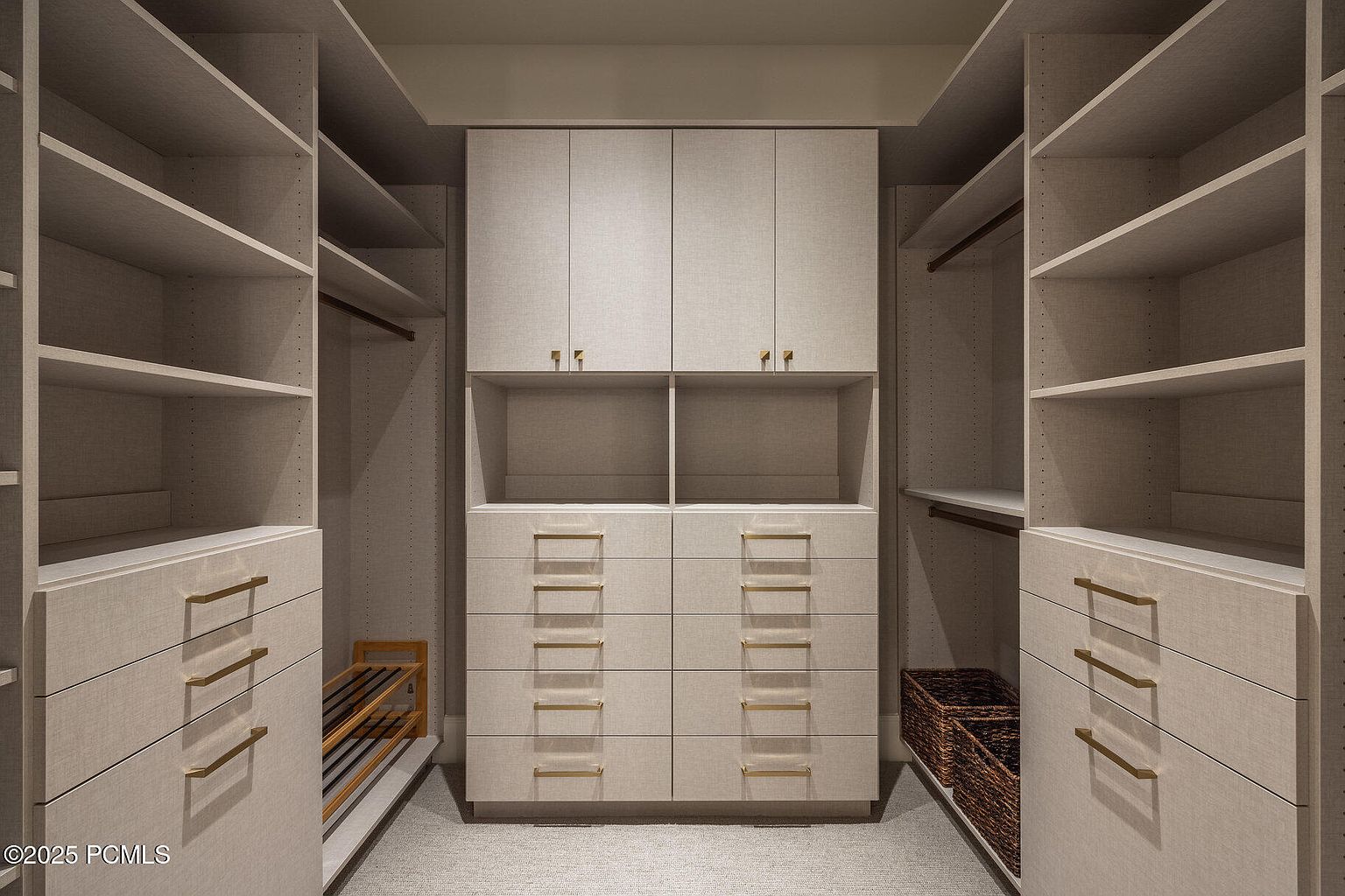 This is a well-organized walk-in closet featuring custom shelving, drawers, and cabinets in a neutral color palette. The closet is designed with ample storage space, including hanging rods, shelves for folded items, and drawers with sleek, modern hardware. The overall impression is one of luxury and functionality, perfect for showcasing the home's attention to detail.