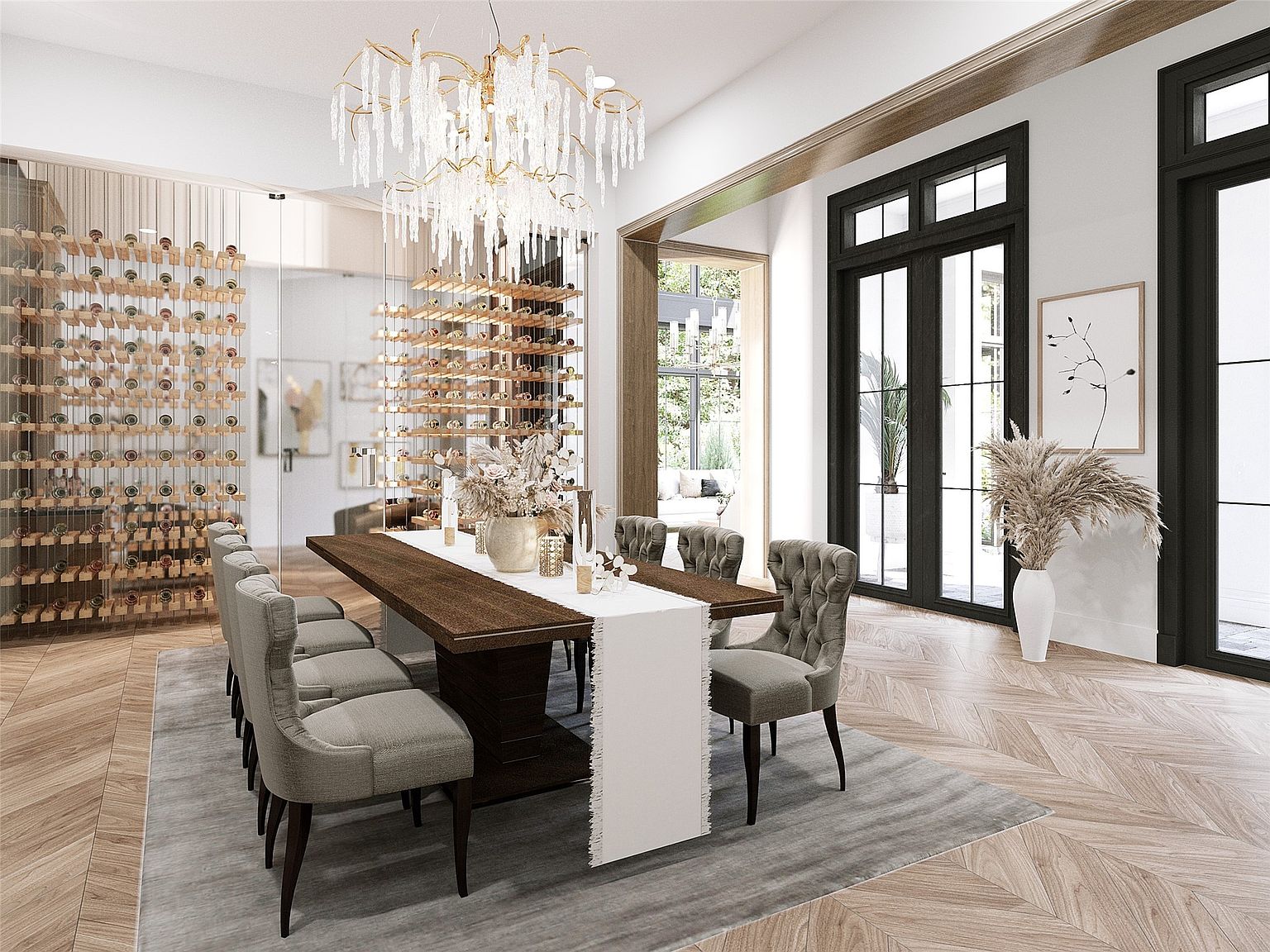 This is an elegant dining room featuring a long wooden table with seating for eight, adorned with a white runner and floral centerpiece. A stunning crystal chandelier hangs above the table, and wine racks are displayed on the left side of the room. The room is well-lit with natural light coming through the large windows and doors, creating a sophisticated and inviting atmosphere.