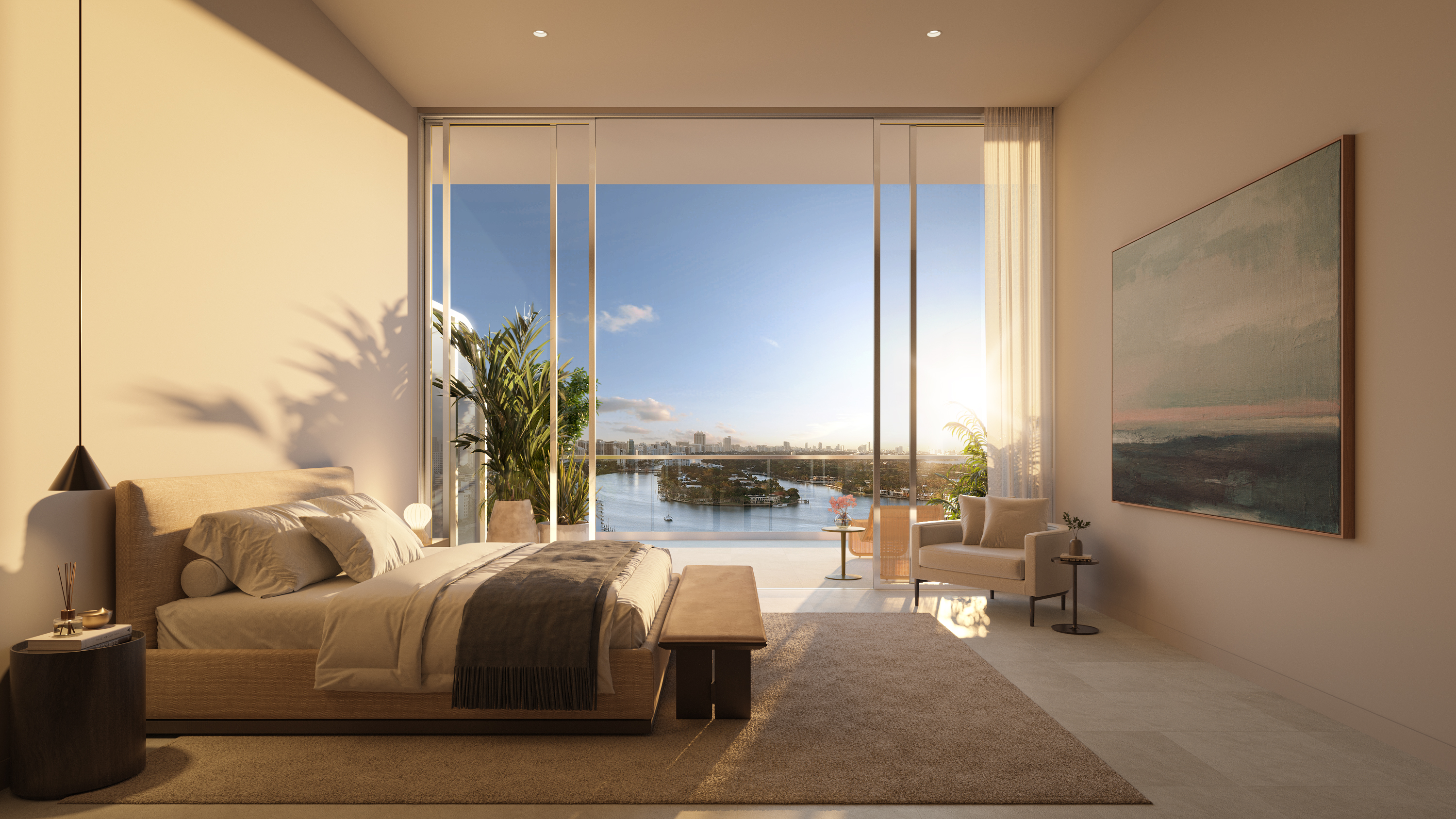 This is a luxurious primary bedroom with a neutral color palette, featuring a large bed with a padded headboard, a bench at the foot of the bed, and a dark wood side table. A large sliding glass door offers stunning views of the water and city skyline, while an armchair and artwork add to the room's elegance. The room is bathed in natural light, creating a serene and inviting atmosphere.