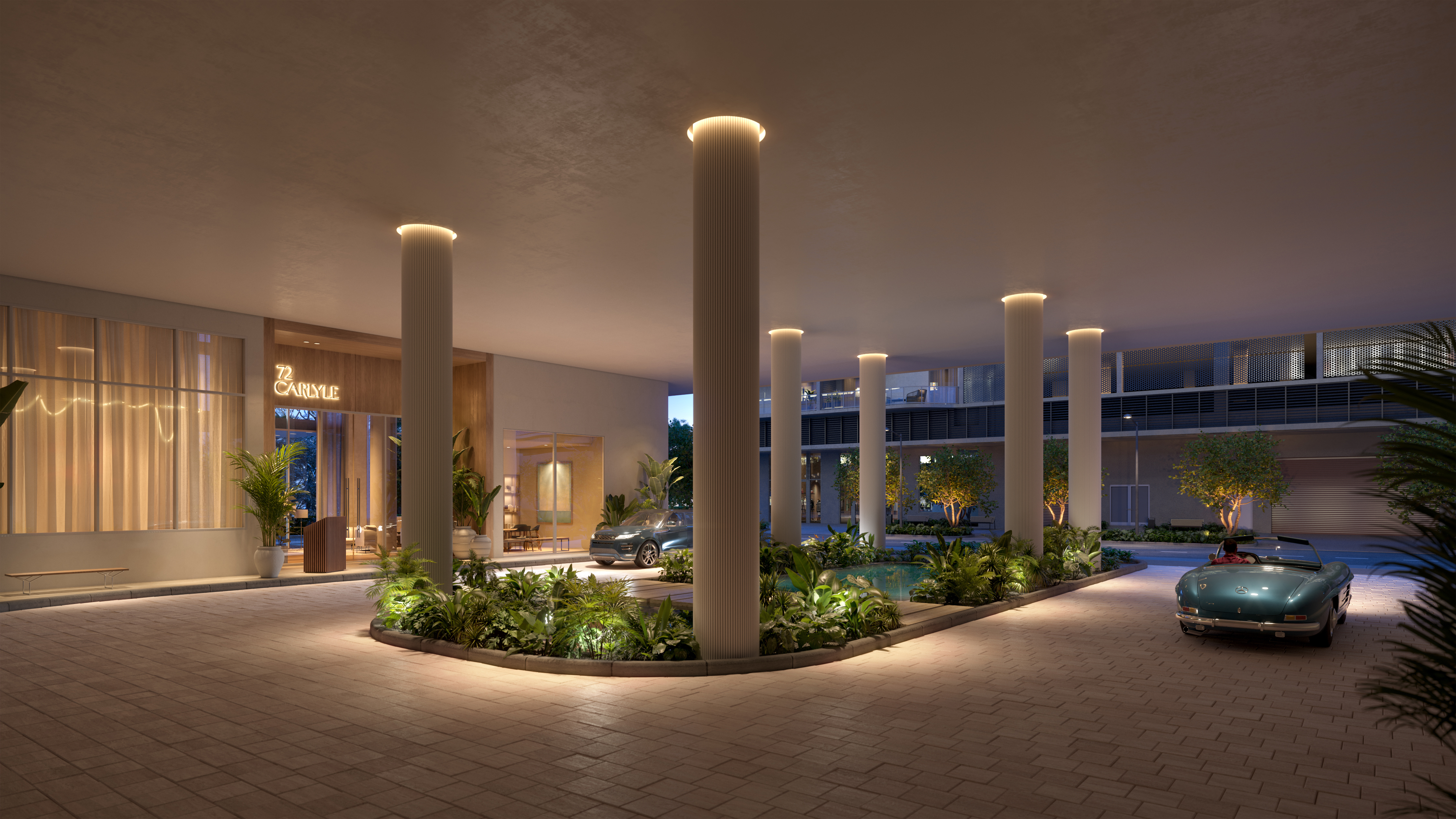 This image showcases a luxurious entryway featuring a covered driveway with brick pavers, supported by elegant columns with integrated lighting. Lush landscaping surrounds a central water feature, adding to the serene ambiance. A classic car is parked nearby, enhancing the upscale feel of the property.