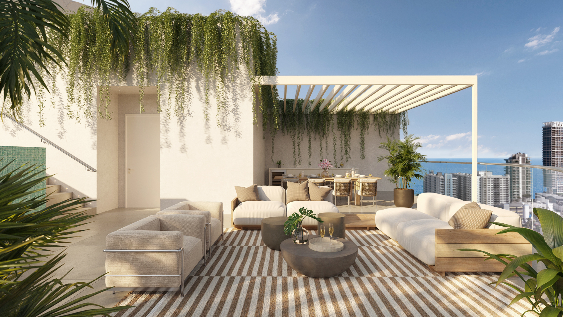 This image showcases a luxurious outdoor living space on a high-rise balcony. The area is furnished with comfortable seating arrangements, including sofas and armchairs, arranged around stylish coffee tables. A dining area is also present, covered by a pergola, and lush greenery adds a touch of nature to the urban setting, with a stunning city and ocean view in the background.