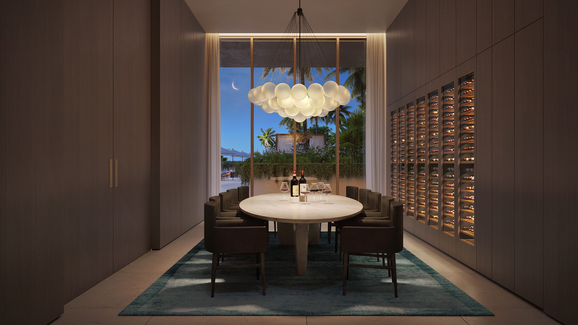 This elegant dining room features a large oval table surrounded by modern chairs, set upon a blue area rug. A unique bubble chandelier hangs above the table, and a wall of wine storage adds a luxurious touch. The room is bathed in soft light, creating a sophisticated and inviting atmosphere, with a view to the outside.