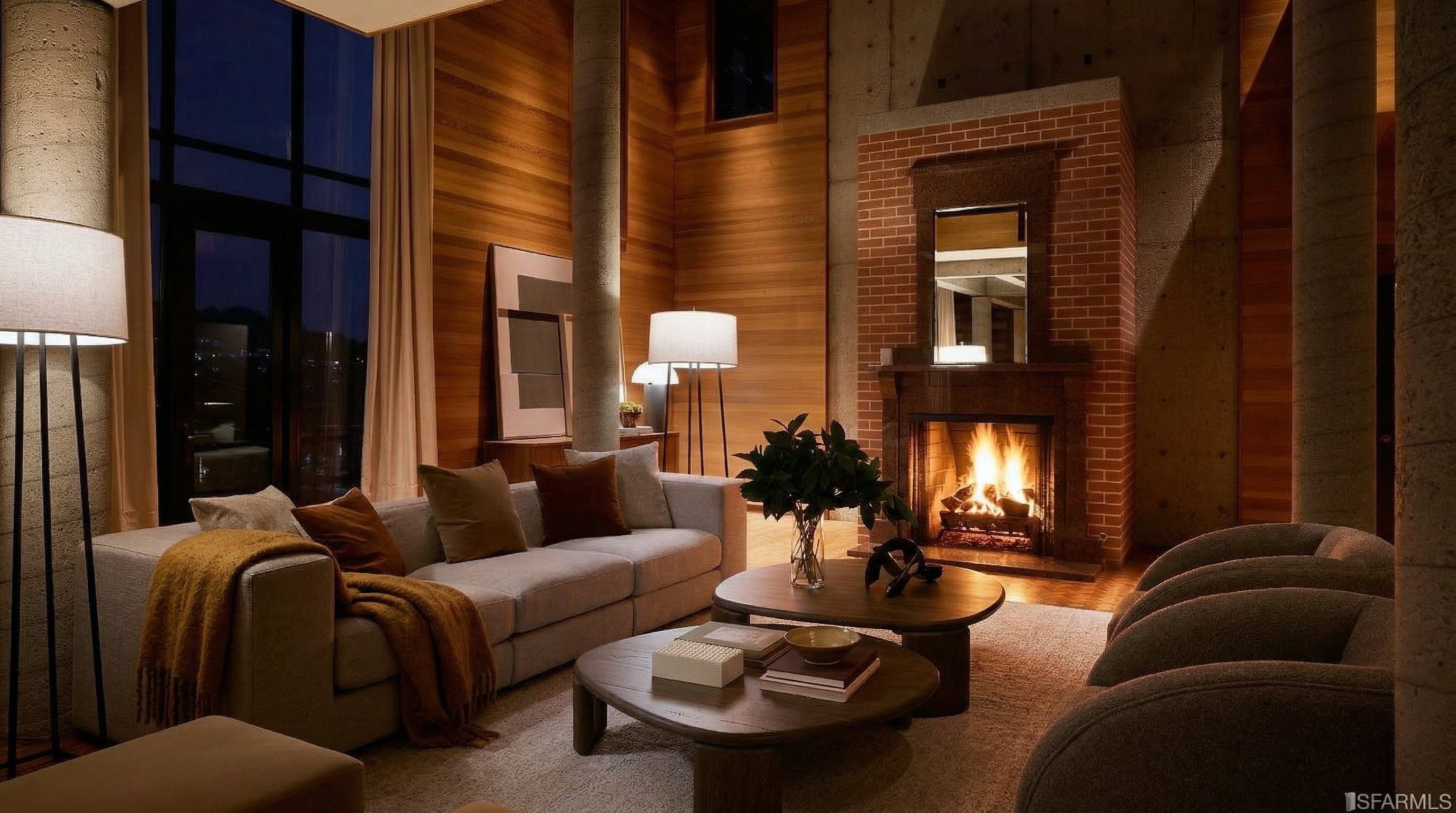 This living room features a modern design with a focus on natural materials. A large sofa is complemented by round coffee tables and armchairs, creating a comfortable seating area. The room is anchored by a brick fireplace and features wood paneling and concrete accents, adding texture and visual interest.
