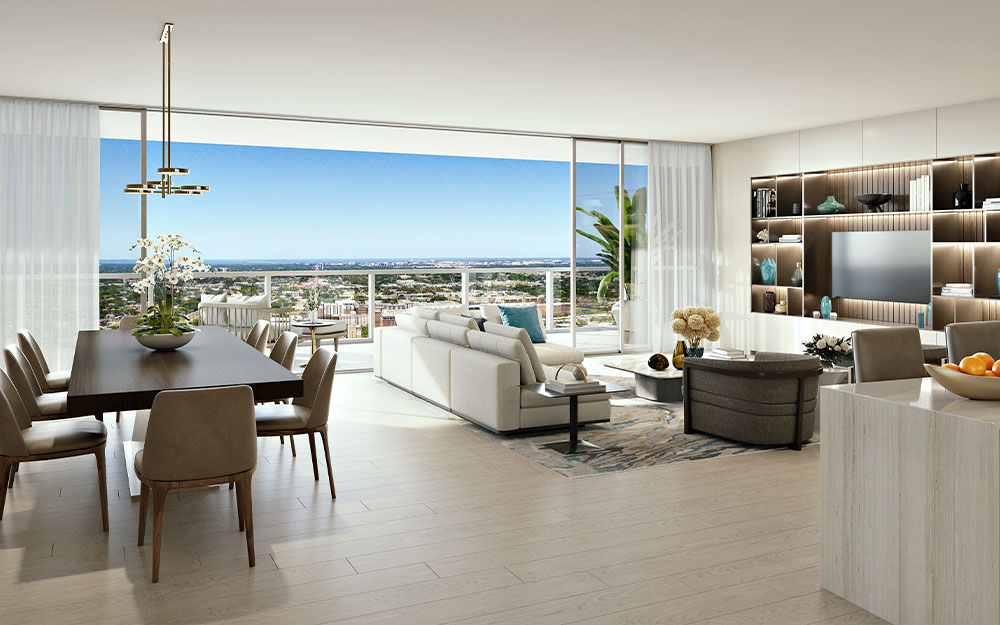 This is a bright and airy open-concept living space featuring a dining area with a dark wood table and modern chandelier, a comfortable white sofa, and a built-in shelving unit with a television. Large sliding glass doors offer panoramic views of the city and bring in ample natural light, enhancing the luxurious and modern feel of the space. The light wood flooring and neutral color palette create a serene and inviting atmosphere.