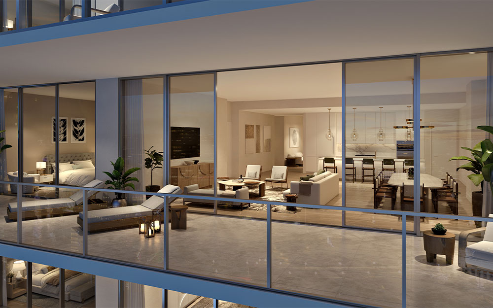 This image showcases a luxurious balcony that seamlessly connects indoor and outdoor living spaces. The balcony features modern lounge furniture, potted plants, and glass railings offering unobstructed views. Through the sliding glass doors, one can see a well-appointed living room, dining area, kitchen, and bedroom, creating an open and airy atmosphere.