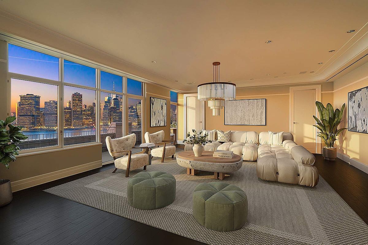 This sophisticated living room features a plush, modular cream-colored sectional sofa and two matching armchairs arranged around a unique, organic-shaped stone coffee table. The space is anchored by a large, textured area rug and illuminated by a striking tiered chandelier, while floor-to-ceiling windows provide a breathtaking, panoramic view of the New York City skyline at dusk. The room exudes a luxurious, contemporary aesthetic with warm neutral tones and high-end finishes, creating an inviting atmosphere for relaxation or entertaining.