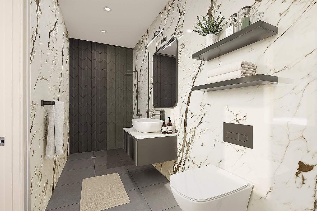 This modern, high-end bathroom features striking white marble-veined walls contrasted by dark charcoal chevron-patterned tiles in the shower area. The space includes a floating vanity with a vessel sink, a sleek wall-mounted toilet, and minimalist floating shelves, all accented by matte black fixtures. The perspective is a wide-angle shot that captures the sophisticated, contemporary design and clean lines of the room.