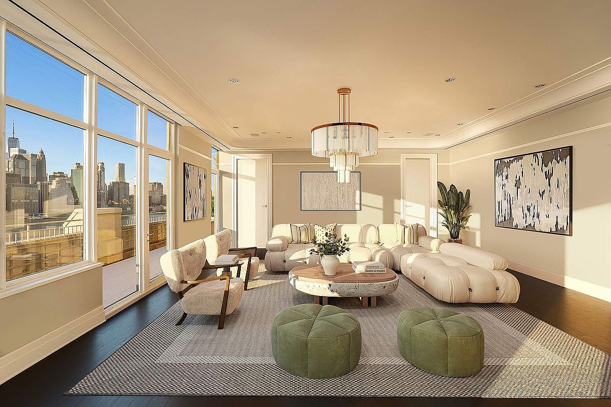 This sophisticated living room features a plush, cream-colored modular sofa and matching armchairs arranged around a unique, textured circular coffee table. The space is anchored by a large, patterned area rug and accented with two sage green ottomans, all illuminated by a striking tiered chandelier. Floor-to-ceiling windows provide an expansive, cinematic view of the New York City skyline, creating a bright and luxurious atmosphere.