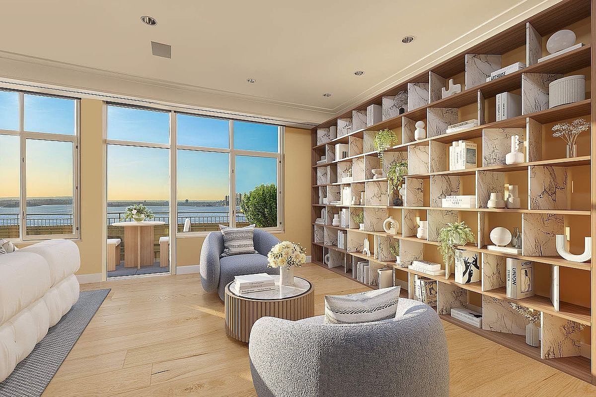 This sophisticated living room features a large, floor-to-ceiling marble-patterned bookshelf that serves as a stunning focal point. The space is furnished with two plush, curved grey armchairs and a matching circular coffee table, all set against a backdrop of expansive windows that offer a panoramic view of the waterfront. The light wood flooring and neutral color palette create an airy, high-end atmosphere perfect for relaxation and entertaining.