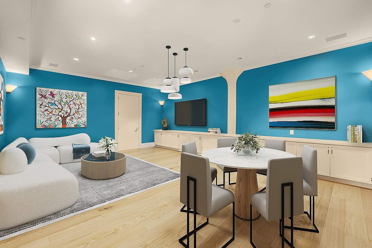 This vibrant open-concept living and dining area features striking turquoise walls contrasted by light hardwood flooring and modern, neutral-toned furniture. The space is anchored by a plush white sectional sofa and a circular marble dining table, illuminated by a contemporary multi-pendant light fixture. The room is decorated with colorful abstract art, creating a bright, energetic, and stylish atmosphere perfect for modern living.