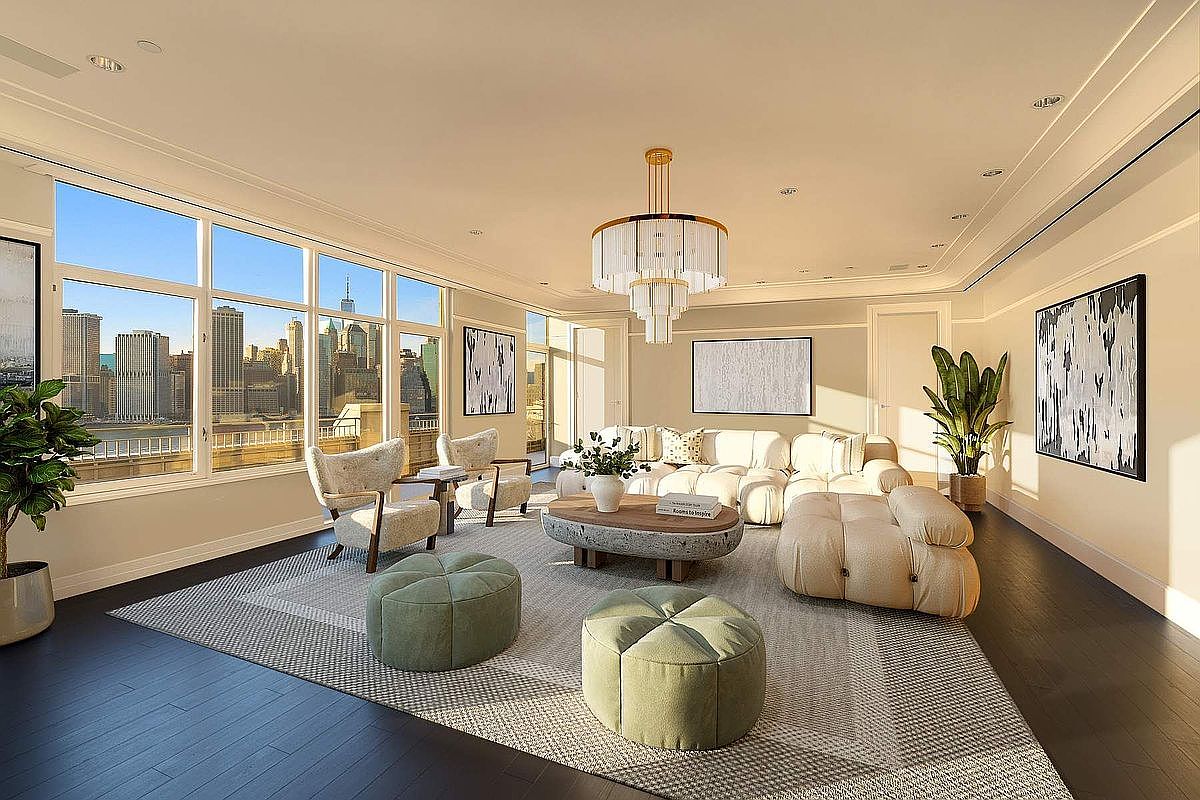 This sophisticated, sun-drenched living room features a contemporary design with a neutral color palette, plush cream-colored modular seating, and a unique stone-textured coffee table. The space is anchored by a large area rug and illuminated by a striking tiered chandelier, while floor-to-ceiling windows offer a breathtaking, panoramic view of the New York City skyline. The room exudes luxury and comfort, perfectly blending modern aesthetics with an iconic urban backdrop.