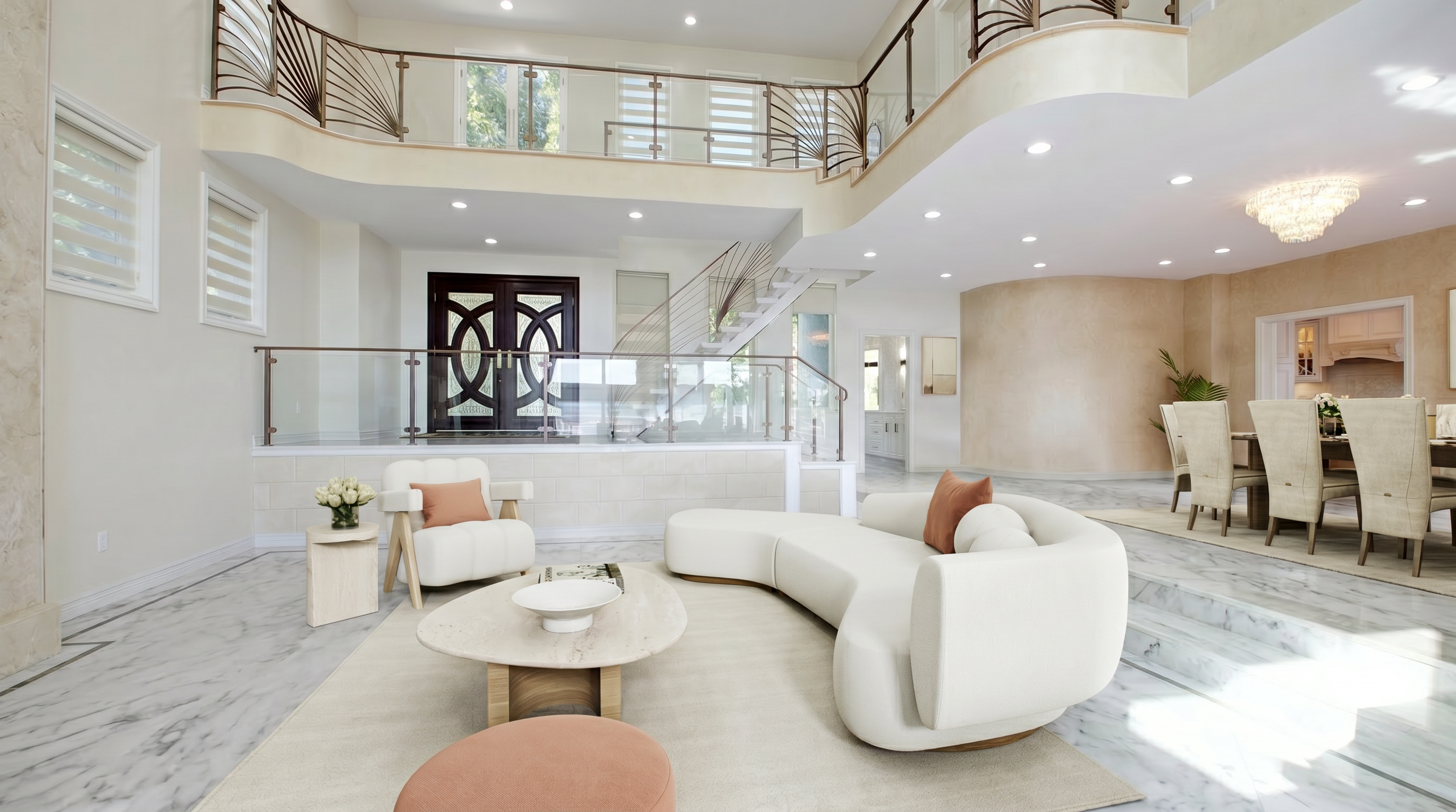 This spacious and elegant living area features a grand, open-concept design with soaring high ceilings and a sophisticated mezzanine level. The room includes a luxurious curved cream sofa, contemporary neutral-toned furniture, and high-end marble flooring, all complemented by a stunning crystal chandelier. The bright, airy layout seamlessly transitions between the elevated entryway and the sunken dining space, creating an opulent and inviting atmosphere.