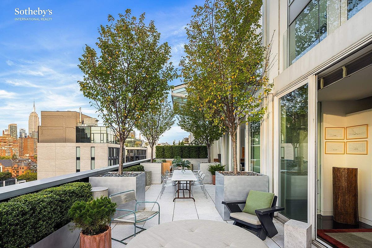 This expansive, modern terrace offers a sophisticated outdoor living space with a dining area, comfortable lounge seating, and mature trees planted in sleek concrete containers. The balcony provides a stunning, elevated view of the New York City skyline, including the iconic Empire State Building, creating a luxurious urban oasis. The clean lines and minimalist aesthetic emphasize a high-end, contemporary lifestyle perfect for entertaining.