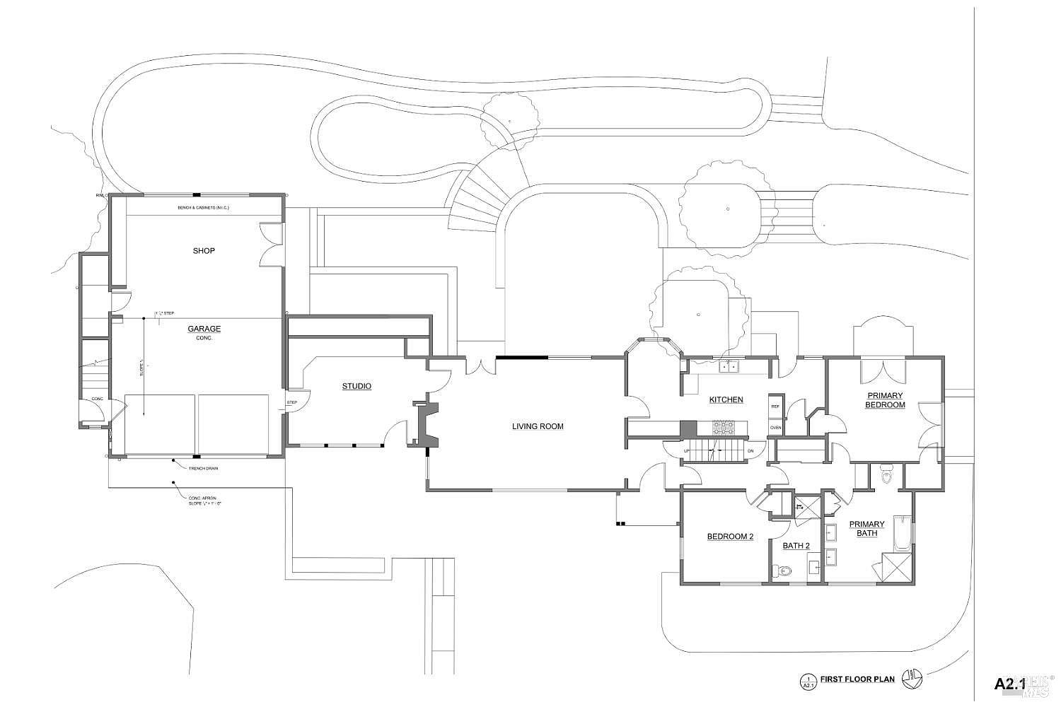 This image is a detailed architectural floor plan for the first level of a residential property. The layout includes a shop and garage area, a central living room, a kitchen, a studio, and two bedrooms, including a primary suite with an attached bath. The drawing provides a clear top-down perspective of the home's spatial organization and flow.