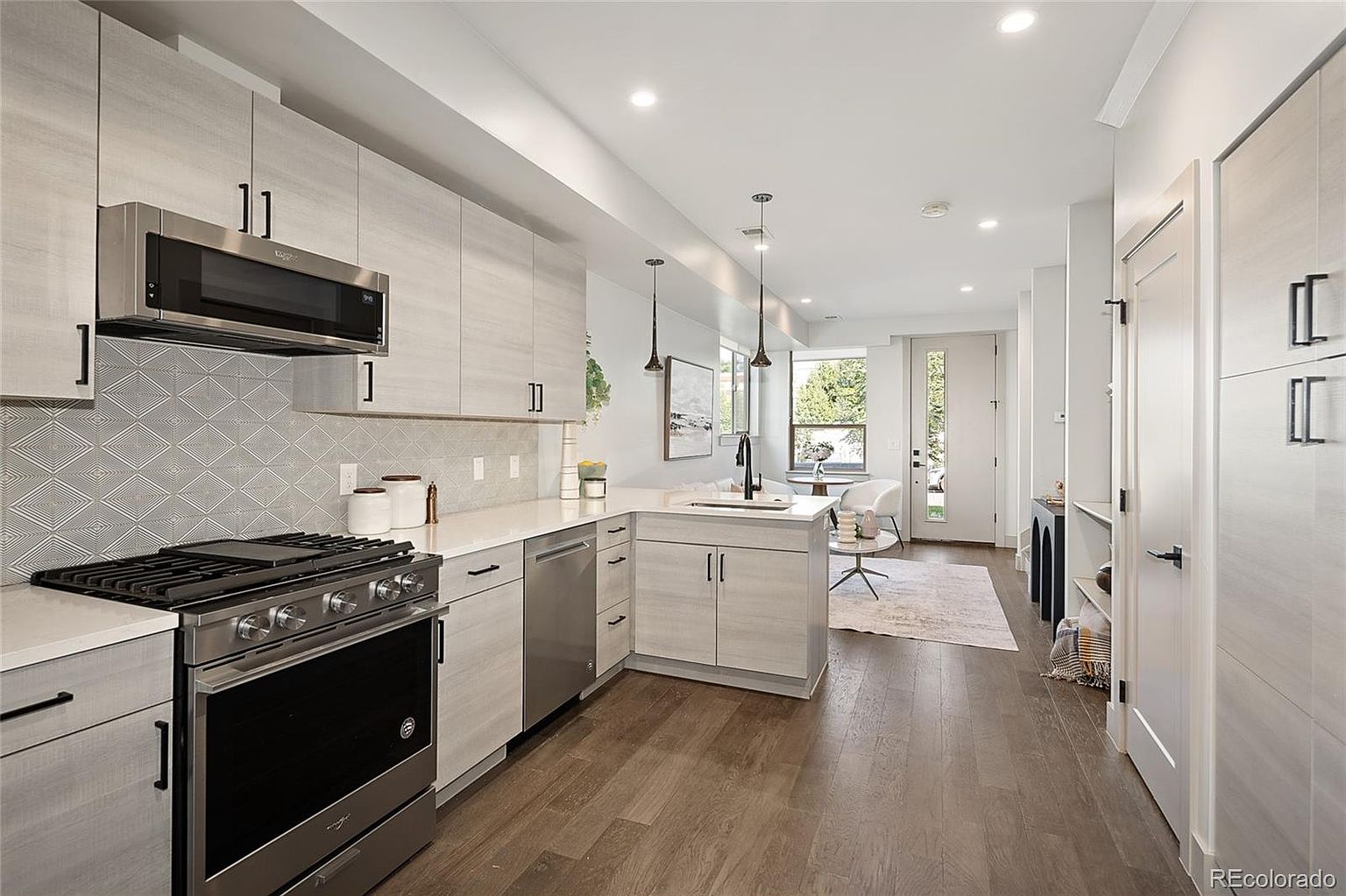 This is a bright and modern kitchen with light wood cabinets, stainless steel appliances, and white countertops. The kitchen features a gas range, built-in microwave, and a dishwasher. The open floor plan seamlessly connects the kitchen to the living area, enhancing the sense of space and flow.