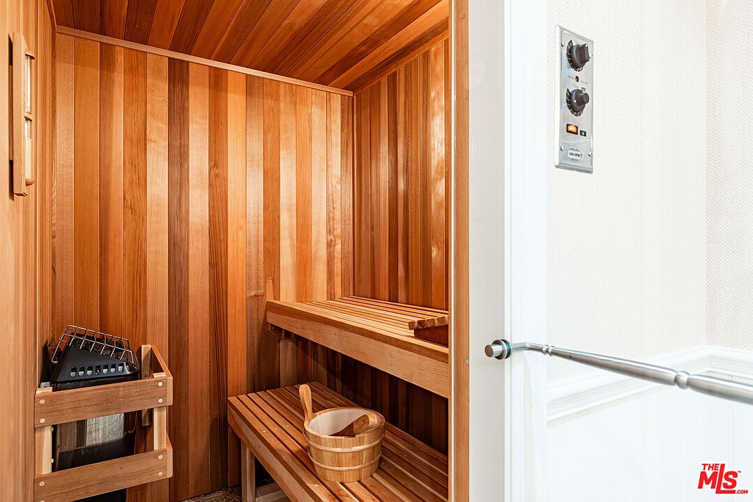 This image showcases a well-maintained sauna, featuring wooden walls, benches, and a traditional wooden bucket and ladle. The sauna heater is visible, suggesting a functional and relaxing space. The overall impression is one of warmth and comfort, highlighting a desirable amenity for potential buyers.