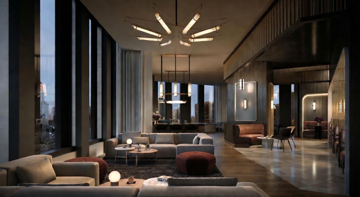 This sophisticated, high-end lounge area serves as a luxury building amenity, featuring a spacious open-plan layout with plush, contemporary sectional seating and warm, ambient lighting. The space is anchored by a striking modern chandelier and floor-to-ceiling windows that offer expansive city views, creating an atmosphere of refined elegance. The interior design blends rich wood tones, textured rugs, and curated accent furniture to provide a comfortable yet upscale social environment.