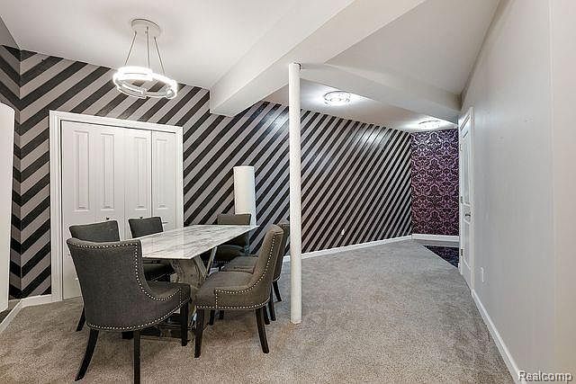 This interior shot showcases a dining room with a modern aesthetic. The walls feature a striking black and gray diagonal stripe pattern, complemented by a contemporary chandelier. A marble-topped dining table is surrounded by upholstered chairs, creating an inviting space for meals.