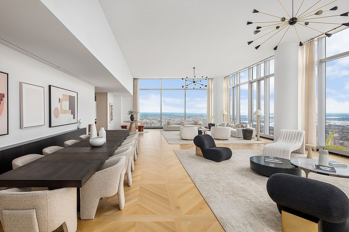 This expansive, high-end open-concept living and dining area features floor-to-ceiling windows that offer breathtaking panoramic city views. The space is defined by its sophisticated, minimalist aesthetic, showcasing light hardwood floors in a chevron pattern, contemporary designer furniture, and striking sculptural chandeliers. The seamless transition between the formal dining area and the plush, sun-drenched lounge creates an atmosphere of refined luxury and airy openness.