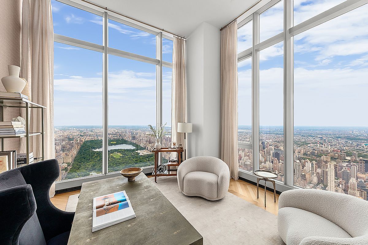 This sophisticated high-rise office space features floor-to-ceiling windows that offer a breathtaking, panoramic view of Central Park and the surrounding New York City skyline. The room is elegantly furnished with a textured desk, two plush cream-colored armchairs, and a sleek metal shelving unit, creating a serene and luxurious atmosphere. The perspective is wide and cinematic, emphasizing the seamless blend of modern interior design with the iconic urban landscape outside.
