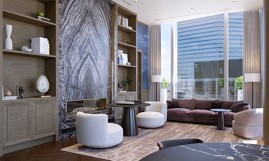 This sophisticated living room features a striking floor-to-ceiling marble fireplace surround flanked by custom wood shelving, creating a luxurious focal point. The space is furnished with a plush, deep-toned sofa and modern, curved accent chairs arranged around a central game table, all set against a backdrop of expansive floor-to-ceiling windows offering an urban cityscape view. The overall aesthetic is one of refined contemporary elegance, blending rich textures and high-end materials to create a serene and upscale atmosphere.