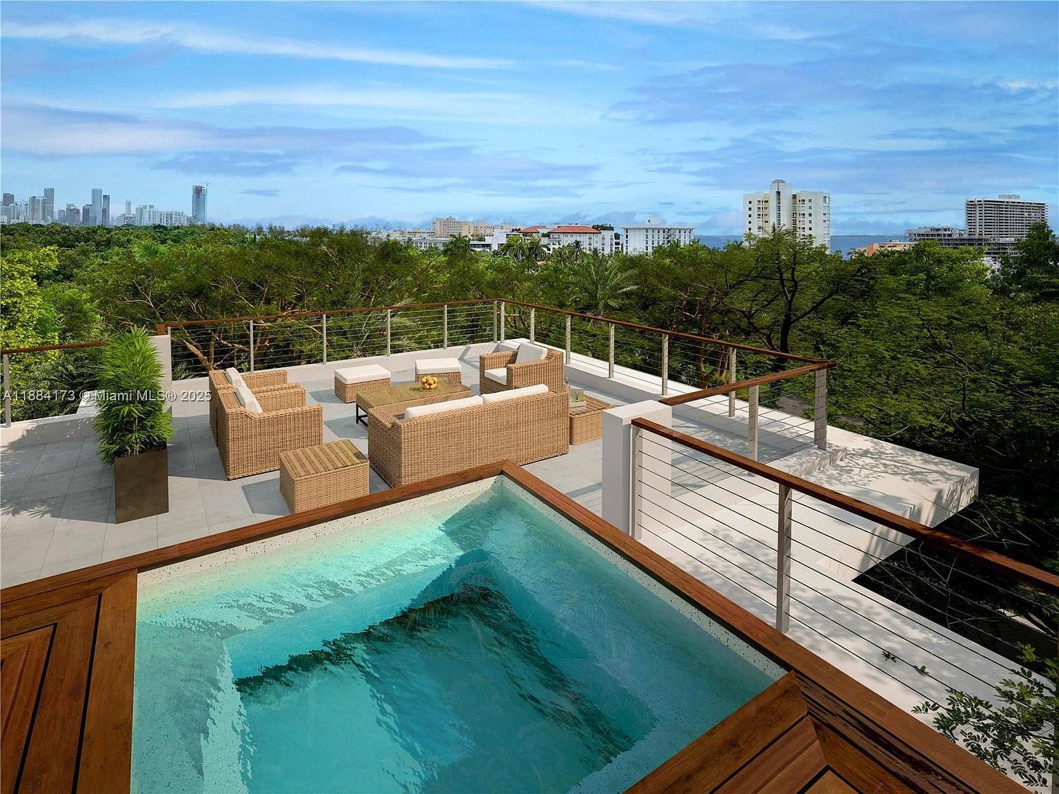 This image showcases a luxurious rooftop pool and lounge area. The pool features a wooden frame and clear blue water, while the lounge area is furnished with wicker seating and a coffee table. The space is surrounded by a modern railing and offers panoramic views of the city skyline and lush greenery, creating an inviting and upscale outdoor living experience.