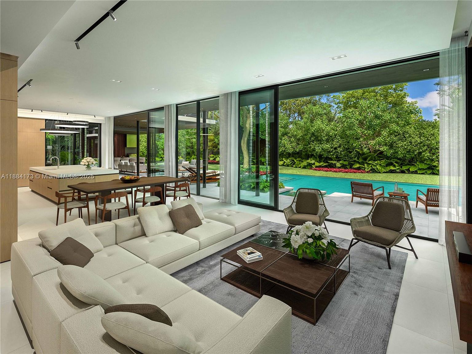 This is a spacious and modern living room with an open floor plan that seamlessly connects to the outdoor pool area through large sliding glass doors. The room features a large sectional sofa, a stylish coffee table, and comfortable armchairs, all set on a neutral-toned rug. The design emphasizes natural light and indoor-outdoor living, creating a luxurious and inviting atmosphere.