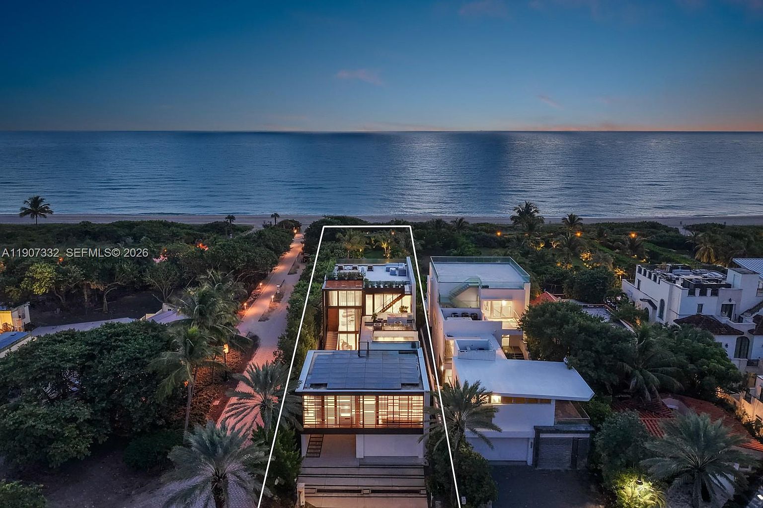This high-angle aerial shot captures a modern, multi-level beachfront residence at twilight, highlighting its sleek architectural design and direct ocean access. The property features a flat roof with solar panels, expansive glass elements, and a tiered layout that maximizes views of the coastline. The surrounding landscape includes lush tropical vegetation and a private path leading toward the sandy beach, creating a serene and luxurious coastal atmosphere.