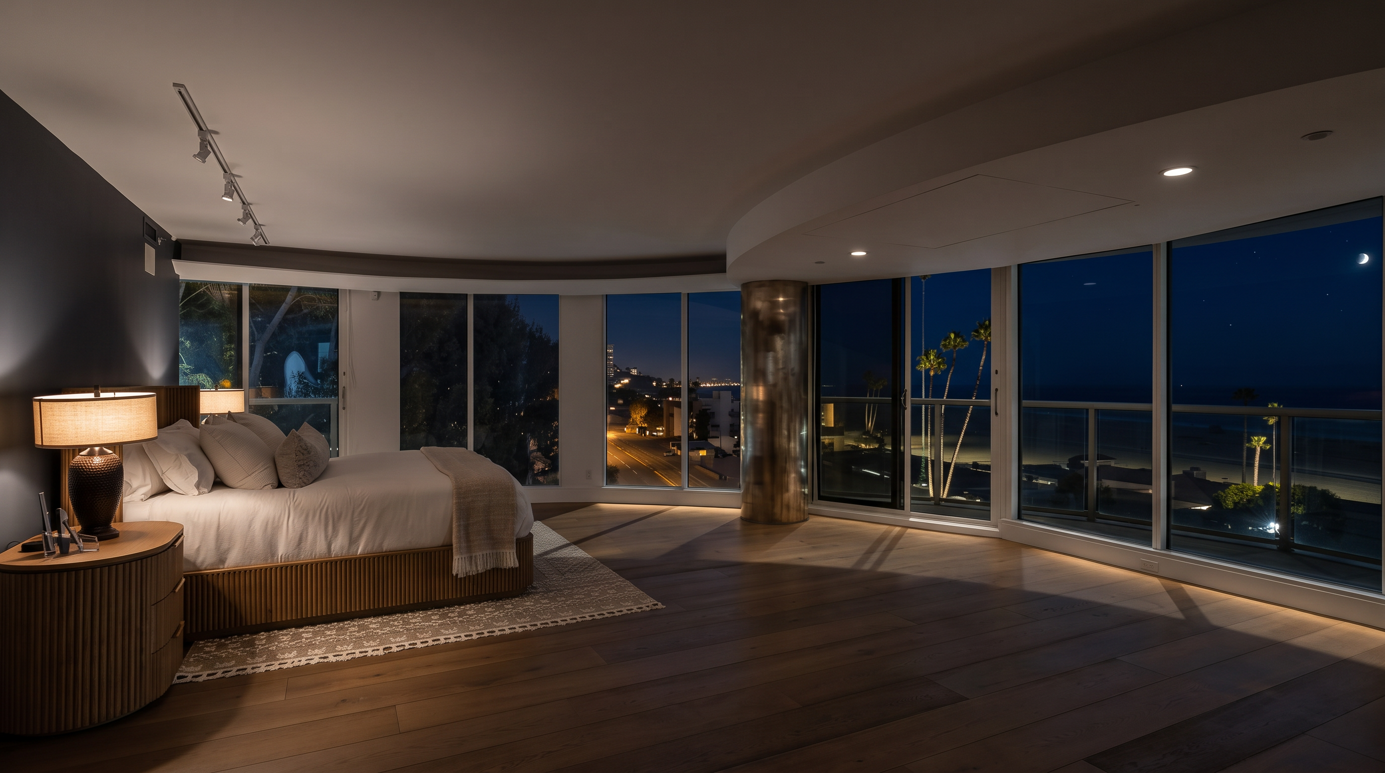 This spacious primary bedroom features light wood flooring and a neutral color palette, centered around a bed with a textured headboard and a patterned rug. The room is defined by a curved wall of large windows that provide expansive, unobstructed views of the beach and ocean. The perspective is wide and cinematic, capturing the seamless transition between the minimalist interior design and the coastal scenery outside.
