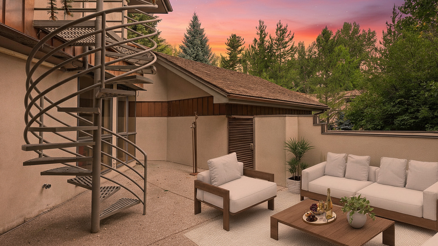 This image showcases a stylish patio area, perfect for outdoor living and entertaining. The space is furnished with a comfortable sofa, armchair, and coffee table adorned with decorative items like wine and greenery. A unique spiral staircase adds an architectural element, while the surrounding trees and colorful sky evoke a sense of privacy and tranquility.