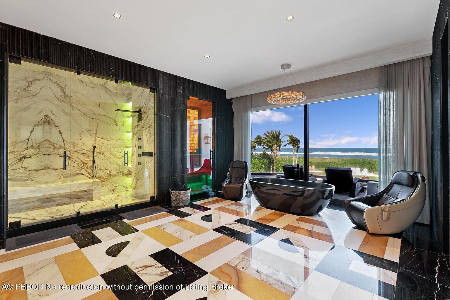 This is a luxurious primary bathroom featuring a modern freestanding bathtub, a spacious glass-enclosed shower with marble walls, and stylish lounge chairs. The floor is adorned with a unique geometric tile pattern, and a large window offers stunning ocean views. The overall impression is one of opulence and relaxation.