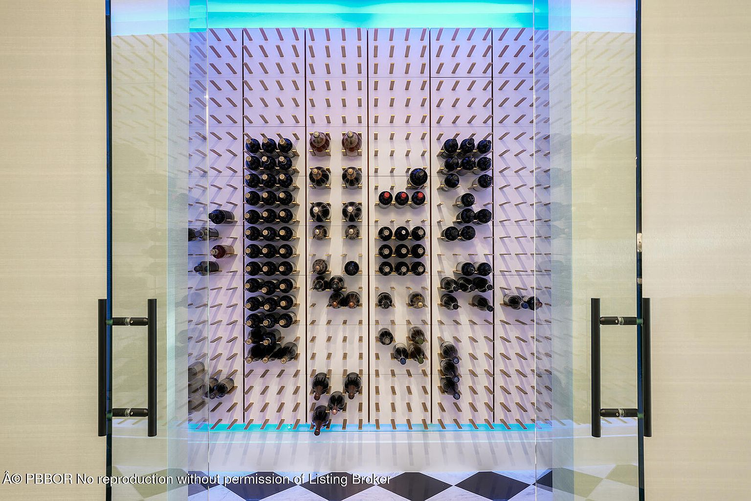 This image showcases a modern wine cellar with a unique display system. Wine bottles are neatly arranged on a wall-mounted rack with individual pegs, creating a visually appealing pattern. The cellar is enclosed by glass doors with sleek, dark handles, and the lighting highlights the collection, adding a touch of sophistication.