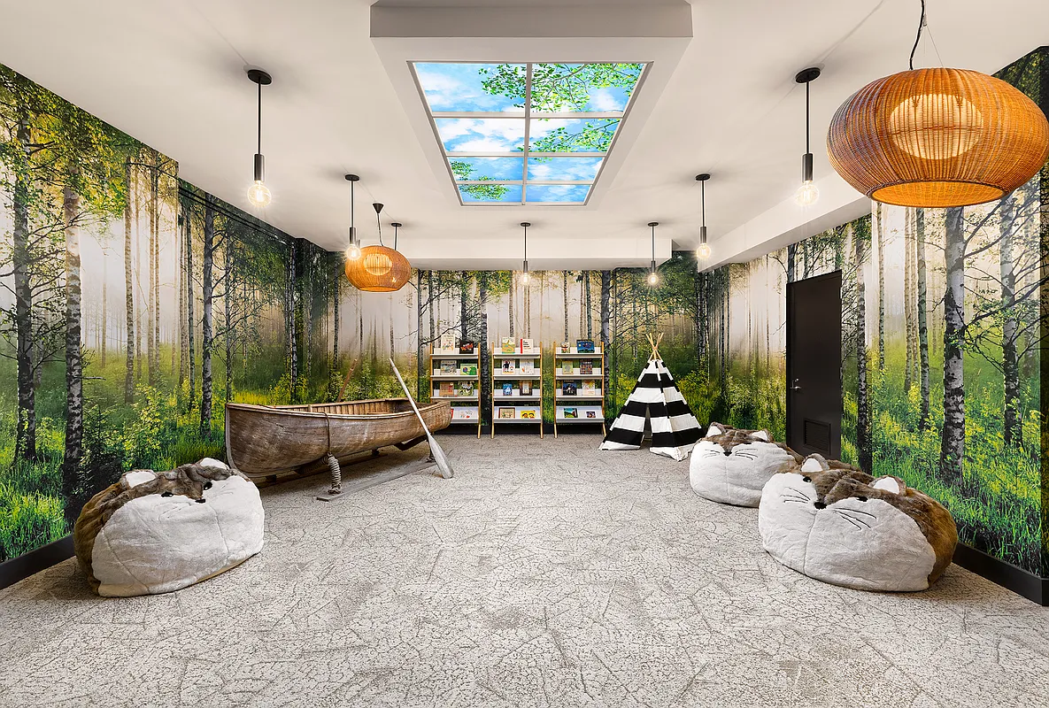 This is a whimsical living room designed with a nature theme. The walls are decorated with a birch forest mural, and the room features a wooden canoe, teepee, and round beanbag chairs shaped like animals. The ceiling incorporates a faux skylight with a view of clouds and tree branches, creating an indoor nature playspace.