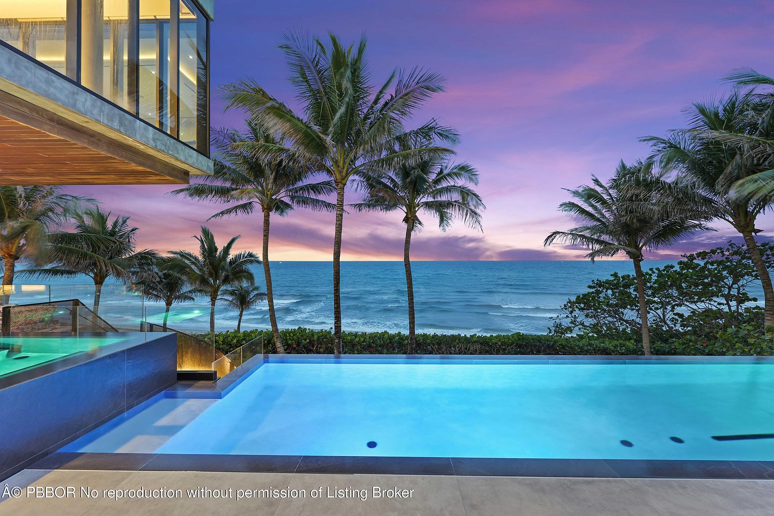 This image showcases a luxurious infinity pool overlooking the ocean at sunset. Palm trees line the beach, creating a tropical paradise. The modern architecture of the adjacent building adds a touch of sophistication, making this an ideal setting for relaxation and entertainment.