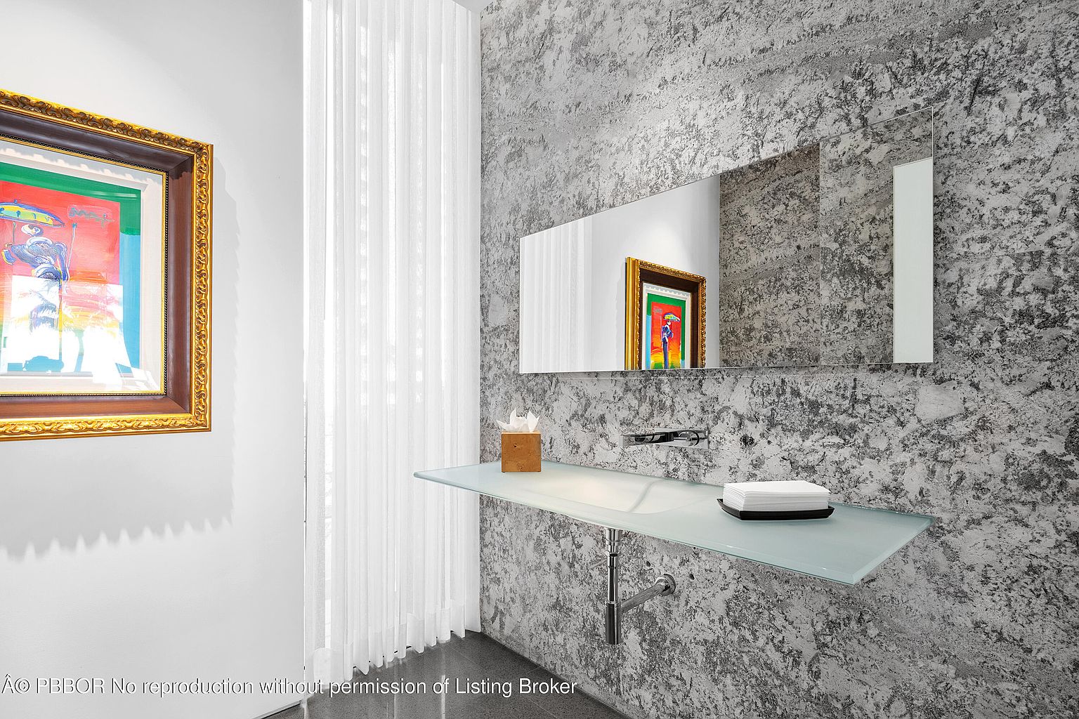 This is a modern guest bathroom featuring a unique textured wall, a floating glass countertop with an integrated sink, and a sleek faucet. A rectangular mirror hangs above the sink, reflecting an artwork. The room has a minimalist and sophisticated design, perfect for a contemporary home.