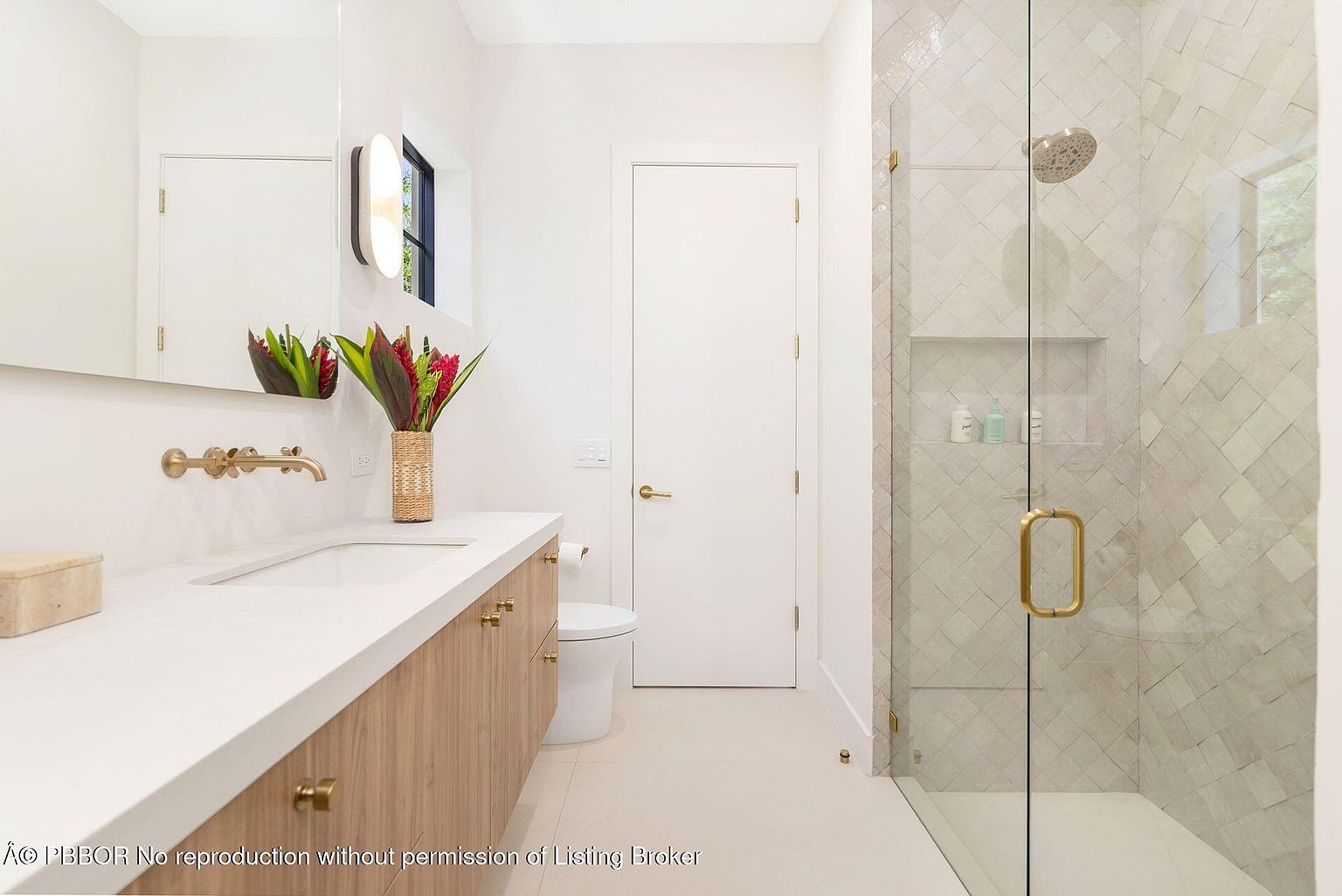 This is a bright and modern bathroom featuring a floating vanity with a white countertop and light wood cabinetry. A large mirror reflects the space, and a glass-enclosed shower with patterned tile adds a touch of elegance. The overall impression is clean, stylish, and well-maintained.