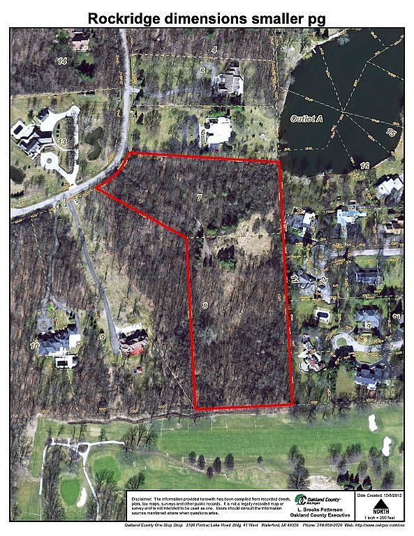 This aerial view showcases a large plot of land, outlined in red, surrounded by residential properties, a golf course, and a lake. The land appears to be heavily wooded, suggesting a natural and private setting. The image provides a clear perspective of the property's dimensions and its proximity to various amenities and natural features.