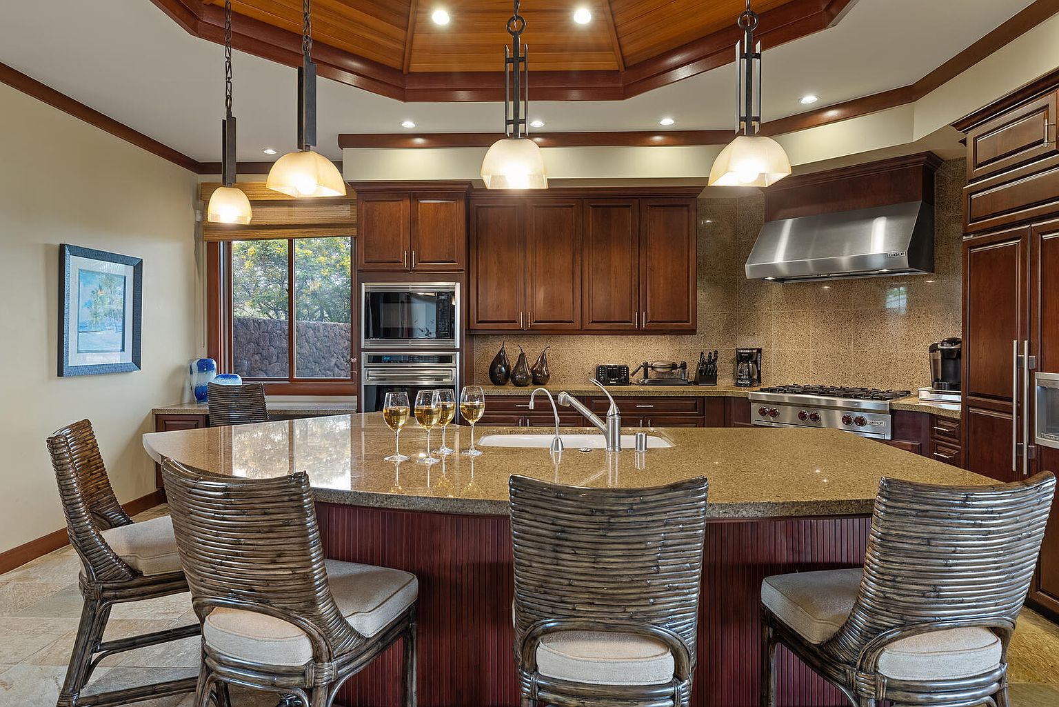 This is a well-appointed kitchen featuring dark wood cabinetry, granite countertops, and stainless steel appliances. A large island with bar seating is the focal point, complemented by pendant lighting. The kitchen exudes a warm and inviting atmosphere, perfect for both cooking and entertaining.