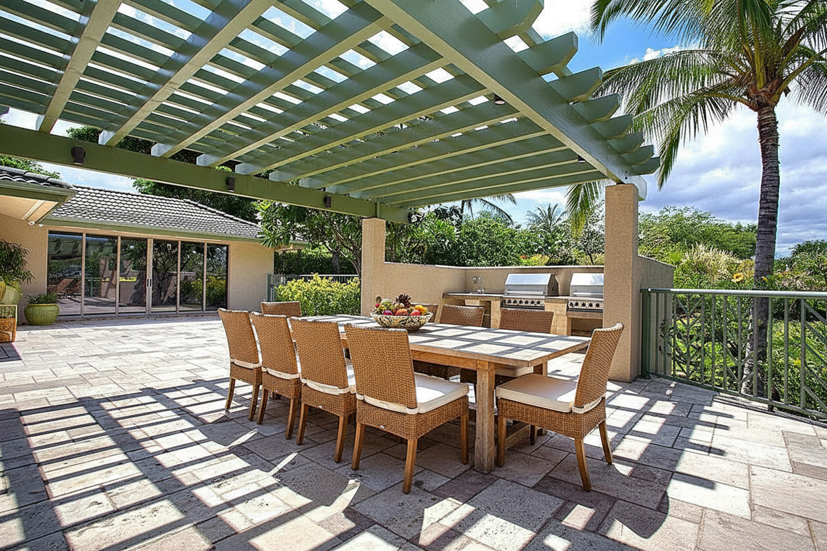 This image showcases a well-appointed outdoor patio area, perfect for entertaining and relaxation. The space features a shaded pergola covering a dining table with seating for eight, along with an outdoor kitchen with stainless steel appliances. The patio is nicely landscaped and offers a private retreat.