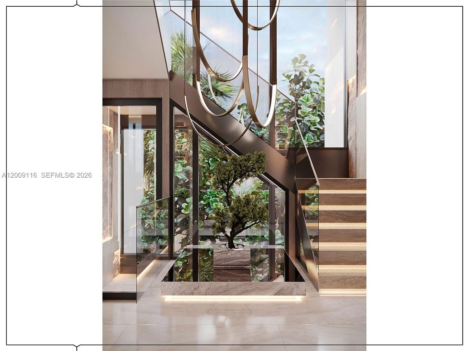 This sophisticated interior space features a striking floating staircase with illuminated treads and a glass railing. A central planter box containing a small tree sits beneath the stairs, framed by large glass panels that look out onto lush greenery. A sculptural, circular chandelier hangs from above, adding a modern artistic element to the bright, open-concept design.