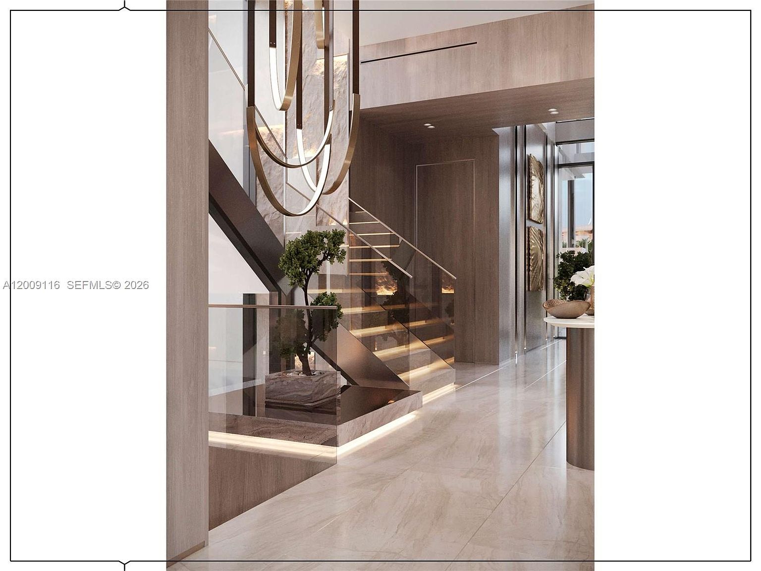 This sophisticated interior space features a striking staircase with glass railings and illuminated wooden treads, serving as the focal point of the entryway. A sculptural, multi-tiered chandelier hangs above a decorative potted tree, while light-toned stone flooring and warm wood-paneled walls create a luxurious, modern atmosphere. The perspective captures the transition from the staircase area into a long, polished hallway, emphasizing the high-end architectural design.