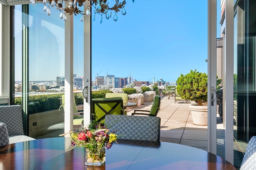 This image showcases a luxurious patio or balcony with a stunning city view. The outdoor space is furnished with comfortable seating and lush greenery, creating an inviting atmosphere. The open sliding doors seamlessly connect the indoor and outdoor living areas, enhancing the sense of spaciousness and elegance.