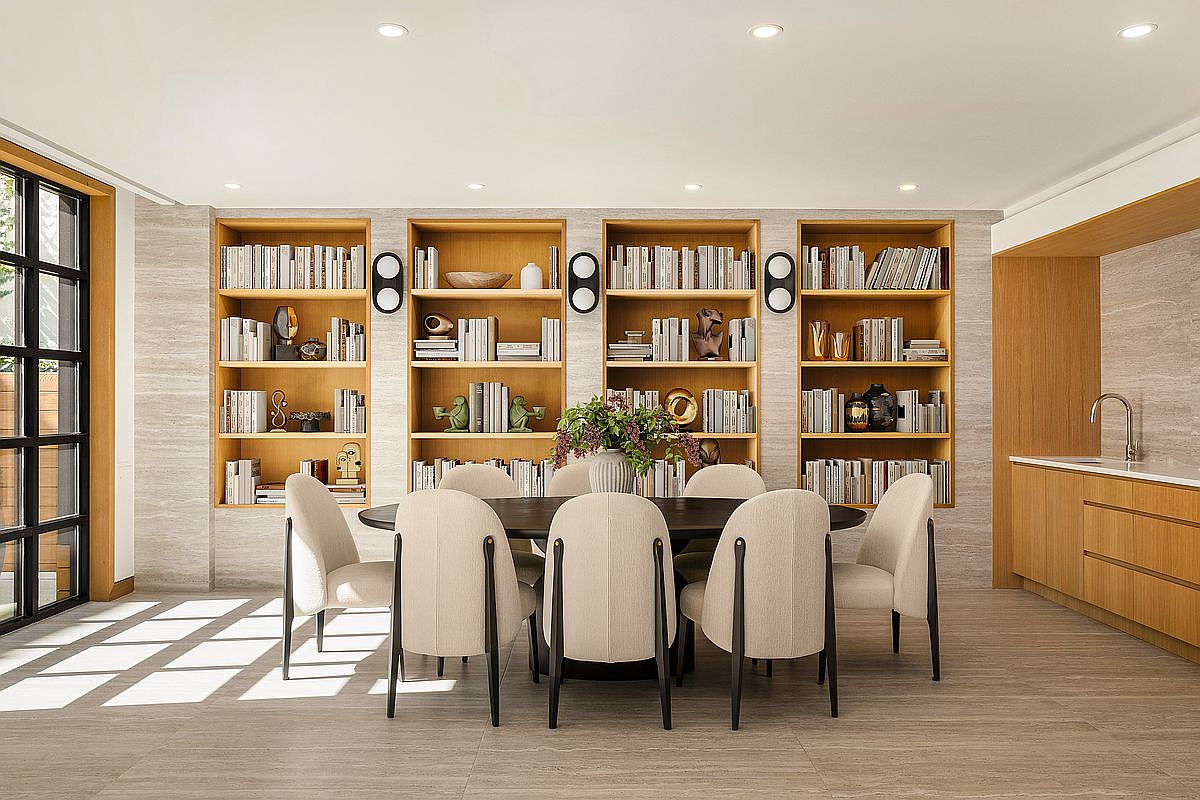 This interior shot showcases a well-appointed dining room featuring a round dark wood table surrounded by upholstered chairs with dark wood legs. Built-in bookshelves line the wall, adding a touch of sophistication and functionality. The room is illuminated by recessed lighting, creating a warm and inviting atmosphere, perfect for family gatherings or formal dinners.