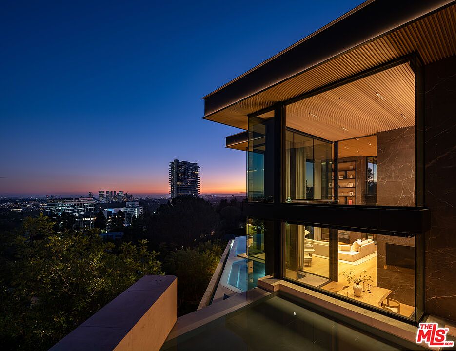 This stunning architectural masterpiece showcases a modern, multi-level residence at twilight, featuring expansive floor-to-ceiling glass walls that seamlessly blend indoor and outdoor living. A sleek infinity-edge pool reflects the vibrant sunset hues and the distant city skyline, creating a sophisticated and luxurious atmosphere. The design emphasizes clean lines, warm wood-paneled ceilings, and a dramatic connection between the home's interior living spaces and the breathtaking panoramic views.