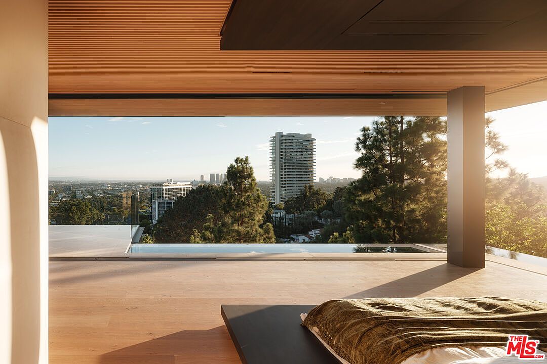 This luxurious primary bedroom features an expansive, seamless indoor-outdoor transition with floor-to-ceiling glass walls that open to a private infinity pool and a panoramic city skyline view. The interior is characterized by warm, minimalist wood-slat ceilings and light hardwood flooring, creating a serene and sophisticated atmosphere. The perspective is captured from within the room, emphasizing the dramatic connection between the high-end living space and the breathtaking natural and urban landscape beyond.