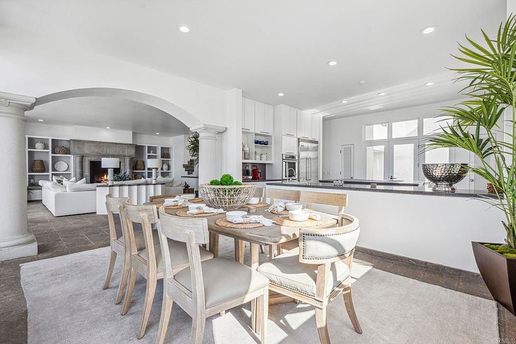 This interior shot showcases a bright and airy dining area adjacent to the kitchen and living room. The dining table is set for a meal, surrounded by stylish wooden chairs with upholstered seats. The open-concept design enhances the flow between the spaces, creating an inviting atmosphere for entertaining and everyday living.