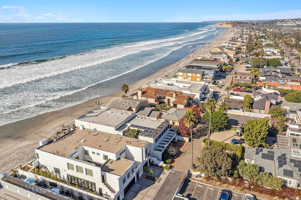 This aerial shot showcases a stunning beachfront property with direct access to the ocean. The homes are nestled along the coastline, offering breathtaking views and a desirable coastal lifestyle. The image highlights the proximity to the beach, the architectural styles of the homes, and the overall serene atmosphere of the neighborhood.